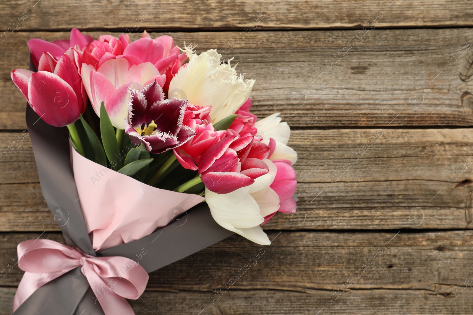 Bouquet of beautiful tulips on wooden background, top view. Space for text Photo of Bouquet of beautiful tulips on wooden background, top view. Space for text