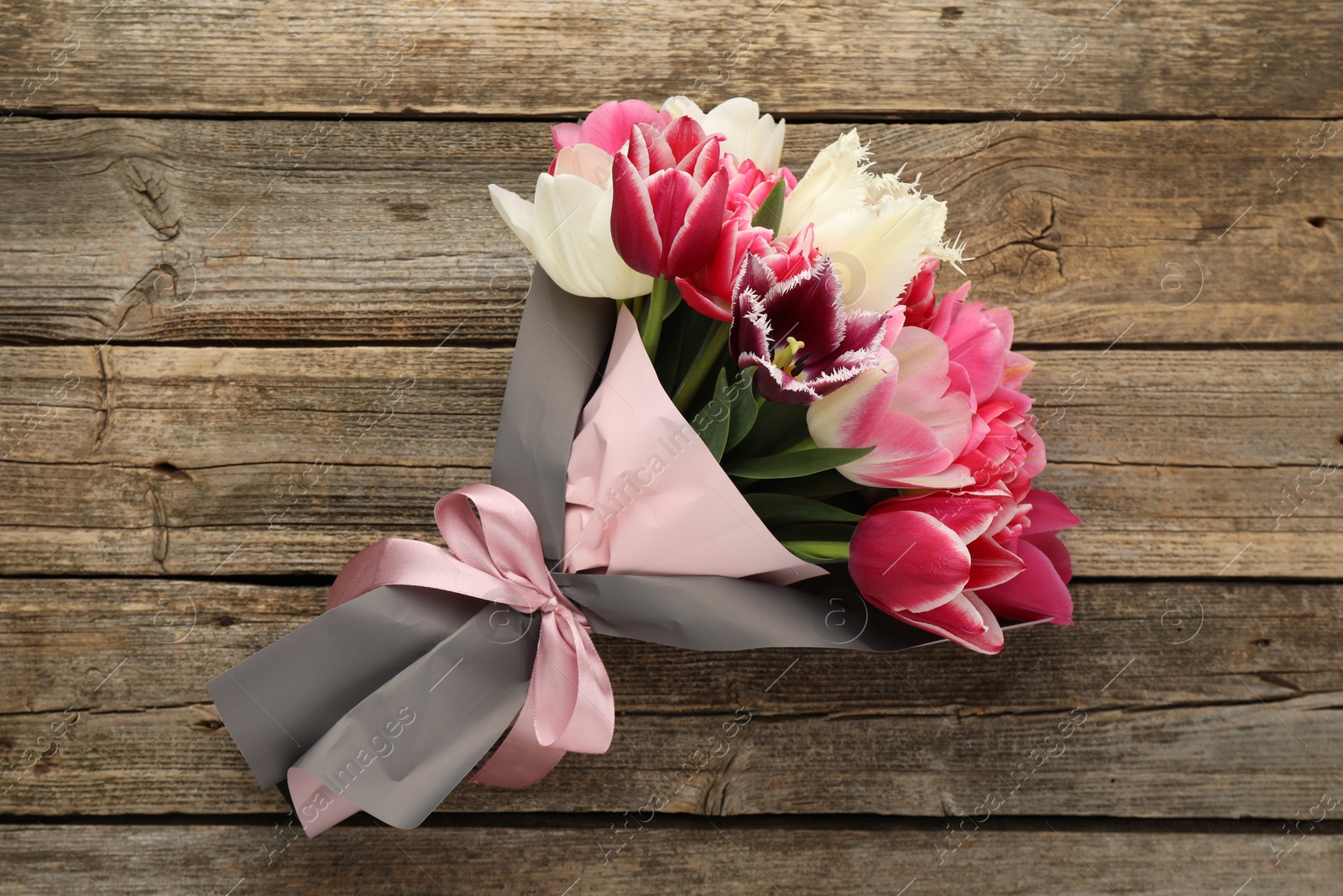 Bouquet of beautiful tulips on wooden background, top view Photo of Bouquet of beautiful tulips on wooden background, top view