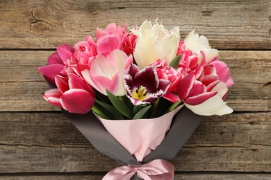 Photo of Bouquet of beautiful tulips on wooden background, top view
