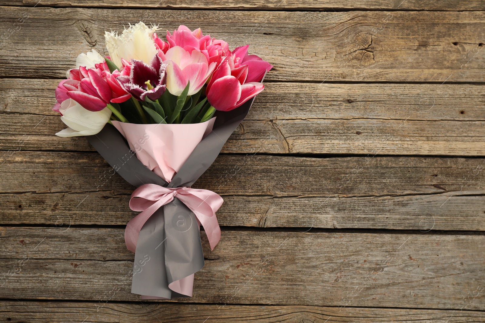 Bouquet of beautiful tulips on wooden background, top view. Space for text Photo of Bouquet of beautiful tulips on wooden background, top view. Space for text