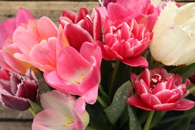 Photo of Beautiful tulip flowers on wooden background, closeup