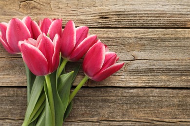 Photo of Beautiful tulips on wooden background, top view. Space for text