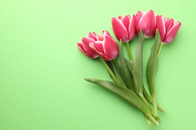 Photo of Beautiful tulip flowers on green background, top view. Space for text