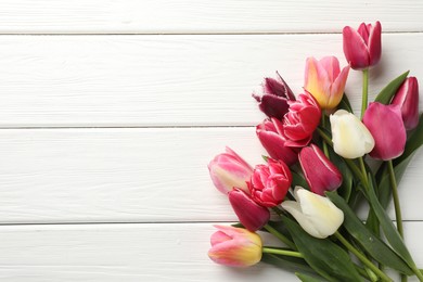 Photo of Beautiful tulips on white wooden background, top view. Space for text