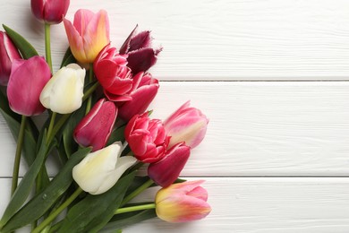 Photo of Beautiful tulips on white wooden background, top view. Space for text
