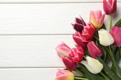 Photo of Beautiful tulips on white wooden background, top view. Space for text
