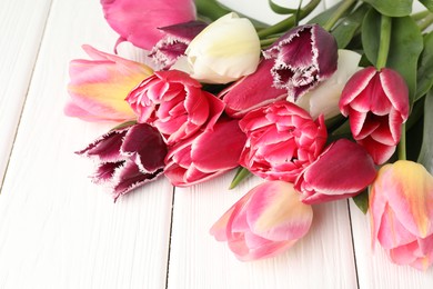 Photo of Beautiful tulips on white wooden background, closeup