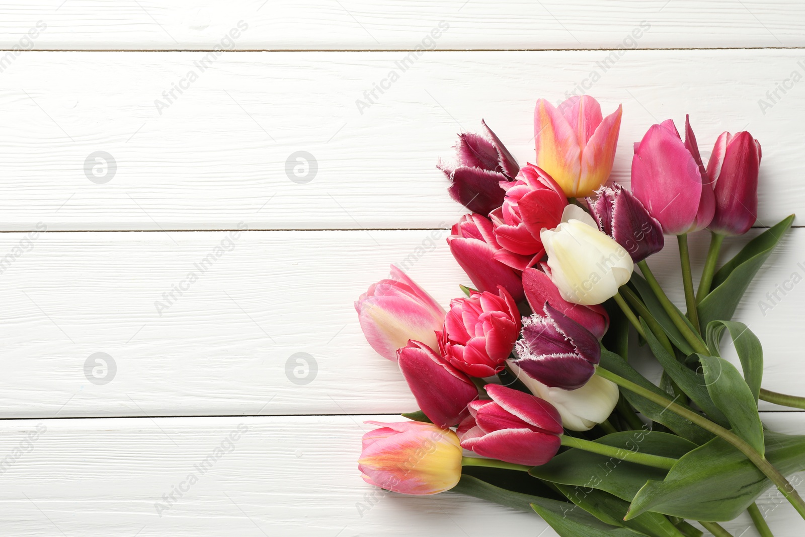 Photo of Beautiful tulips on white wooden background, top view