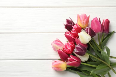 Photo of Beautiful tulips on white wooden background, top view