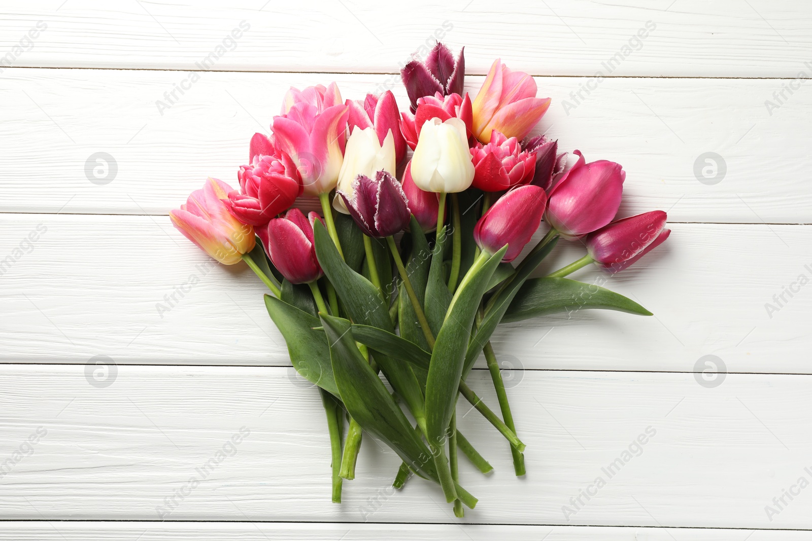 Photo of Beautiful tulips on white wooden background, top view