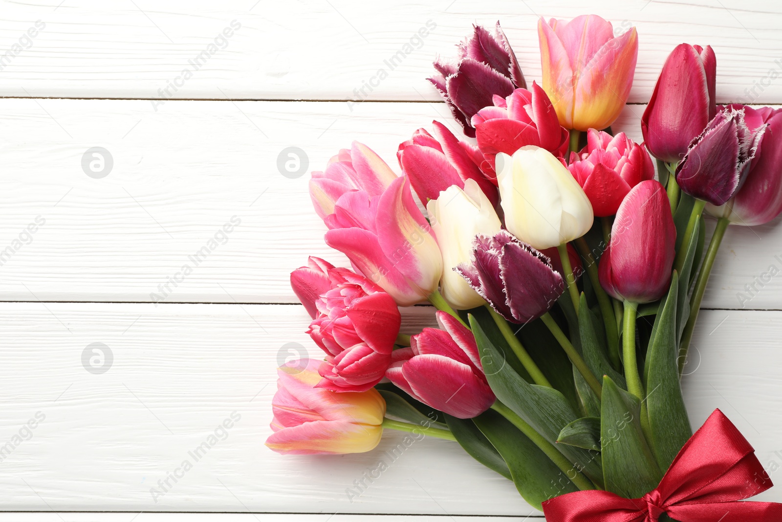Photo of Bouquet of beautiful tulips on white wooden background, top view. Space for text