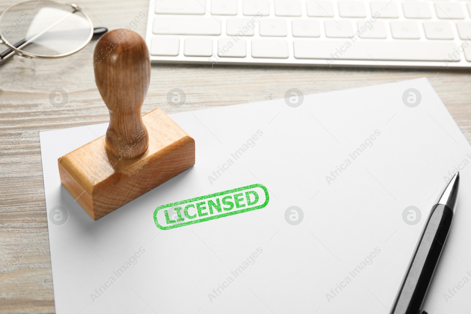 Sheet of paper with word Licensed, stamp, keyboard and pen on white wooden table, closeup Image of Sheet of paper with word Licensed, stamp, keyboard and pen on white wooden table, closeup