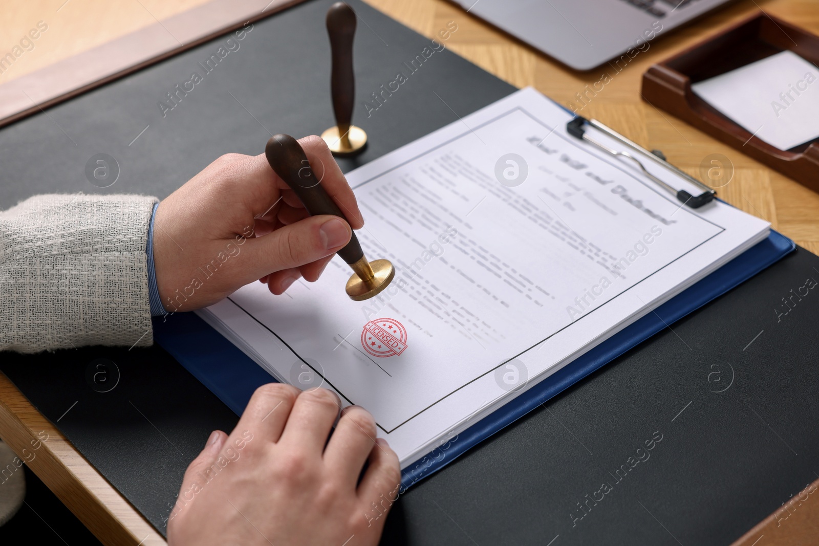 Man stamping document with Licensed stamp at table, closeup Image of Man stamping document with Licensed stamp at table, closeup