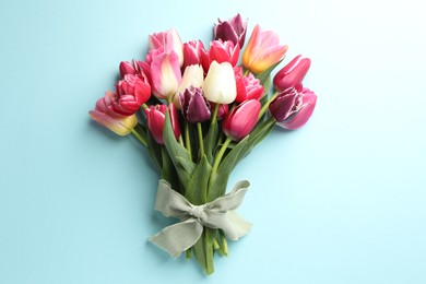 Photo of Bouquet of beautiful tulips on light blue background, top view