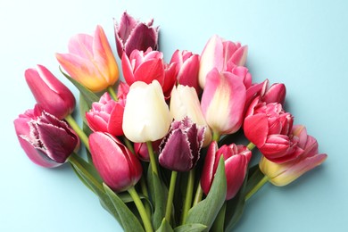 Photo of Bouquet of beautiful tulips on light blue background, top view