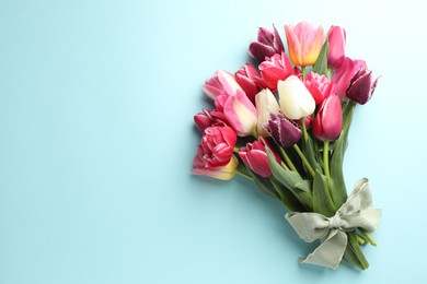 Photo of Bouquet of beautiful tulips on light blue background, top view. Space for text