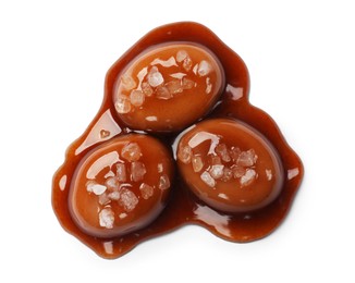 Photo of Tasty sweet candies, salt and caramel sauce isolated on white, top view