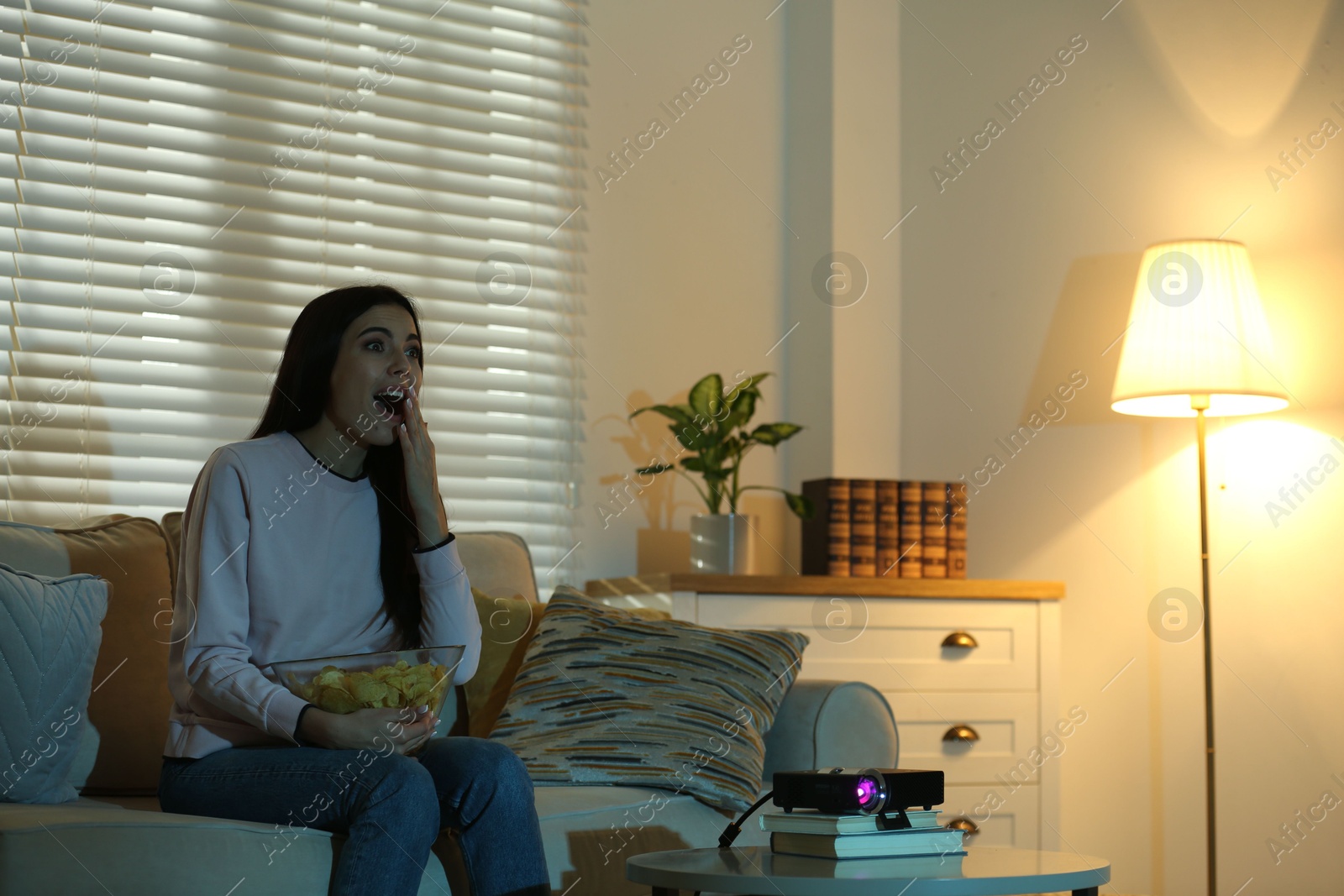 Emotional young woman watching movie using video projector at home Photo of Emotional young woman watching movie using video projector at home