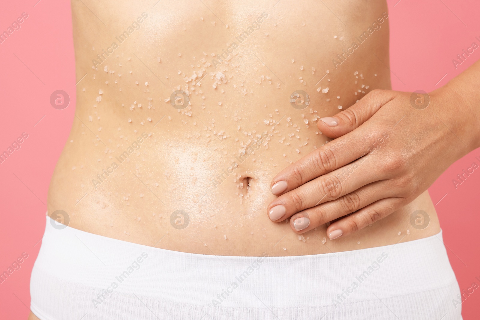 Woman applying body scrub onto her belly against pink background, closeup Photo of Woman applying body scrub onto her belly against pink background, closeup