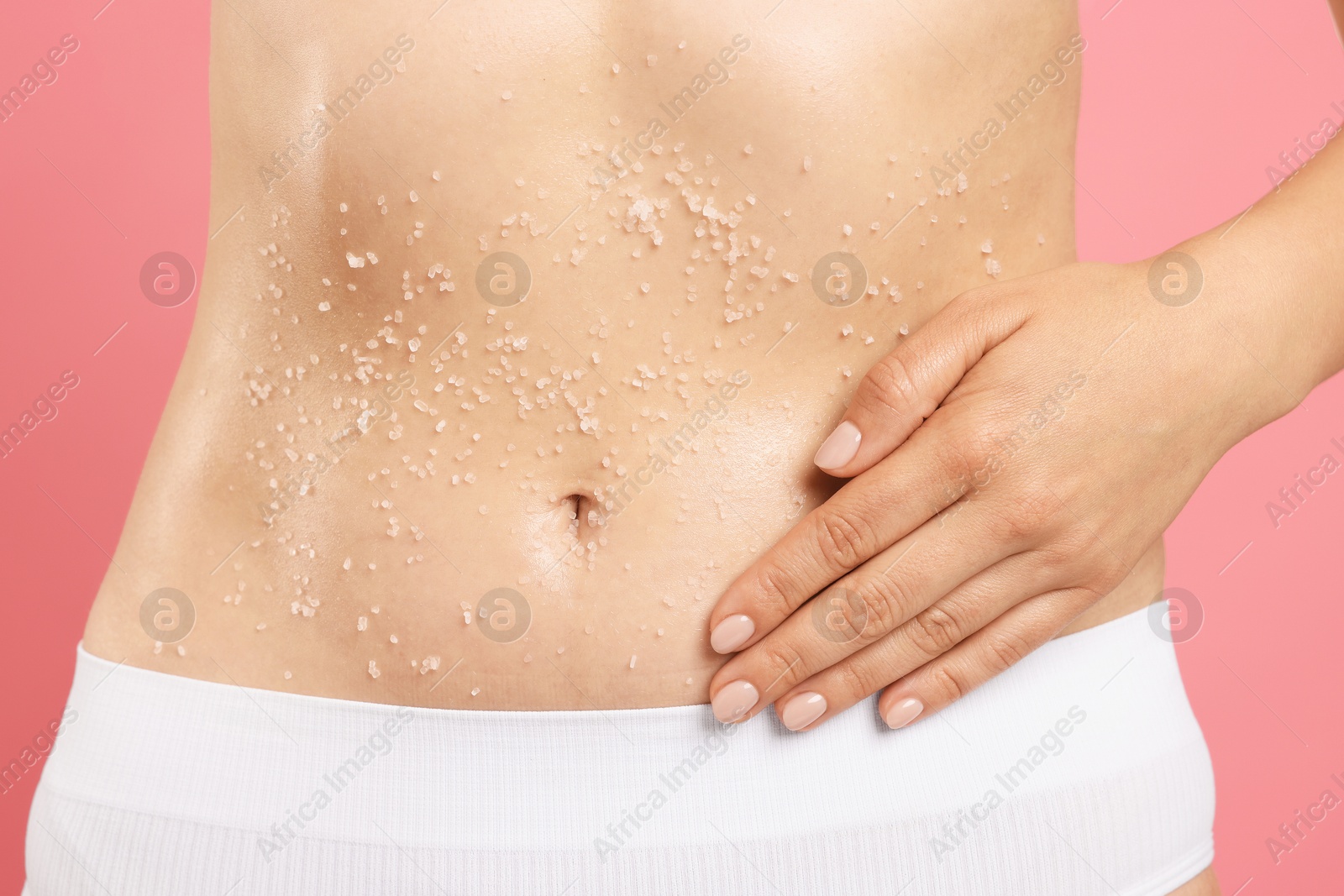 Woman applying body scrub onto her belly against pink background, closeup Photo of Woman applying body scrub onto her belly against pink background, closeup
