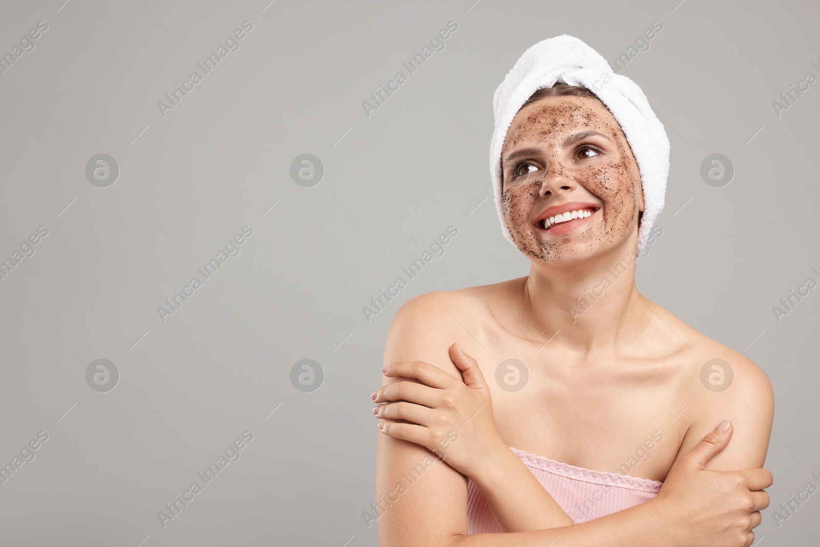 Smiling woman with body scrub on her face against grey background. Space for text Photo of Smiling woman with body scrub on her face against grey background. Space for text