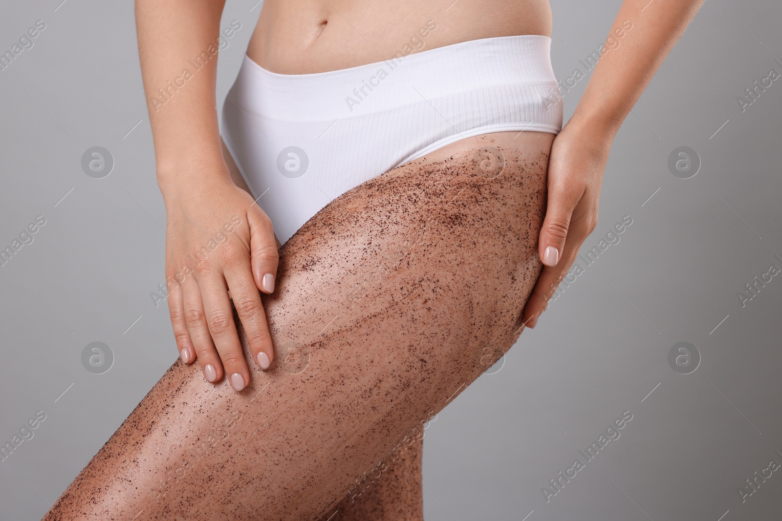 Woman with body scrub on her legs against grey background, closeup Photo of Woman with body scrub on her legs against grey background, closeup
