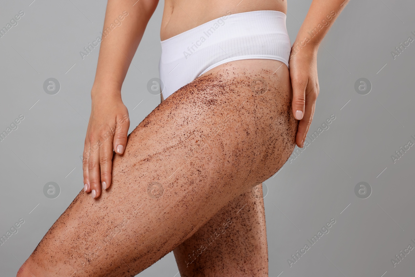 Woman with body scrub on her legs against grey background, closeup Photo of Woman with body scrub on her legs against grey background, closeup