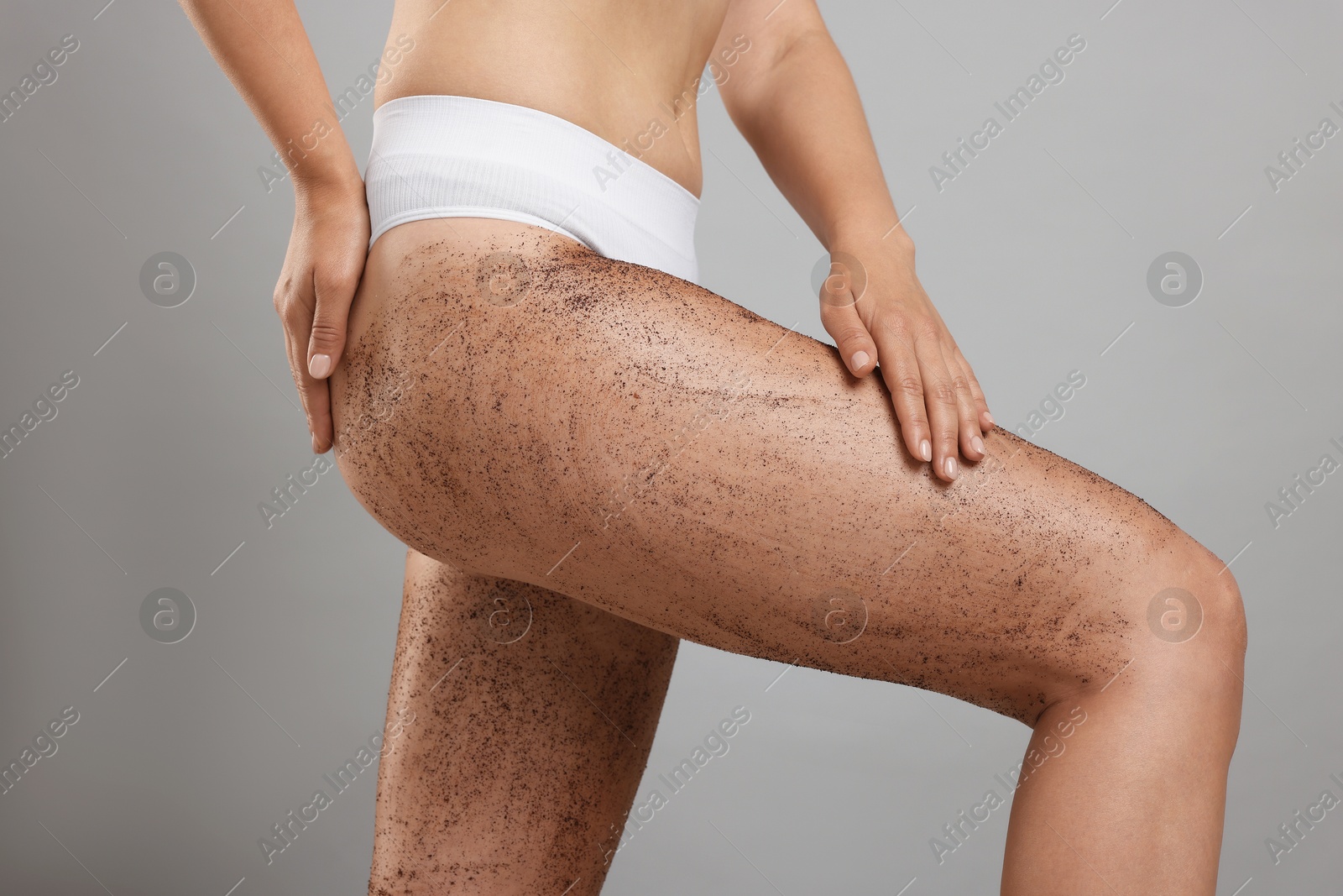 Woman with body scrub on her legs against grey background, closeup Photo of Woman with body scrub on her legs against grey background, closeup