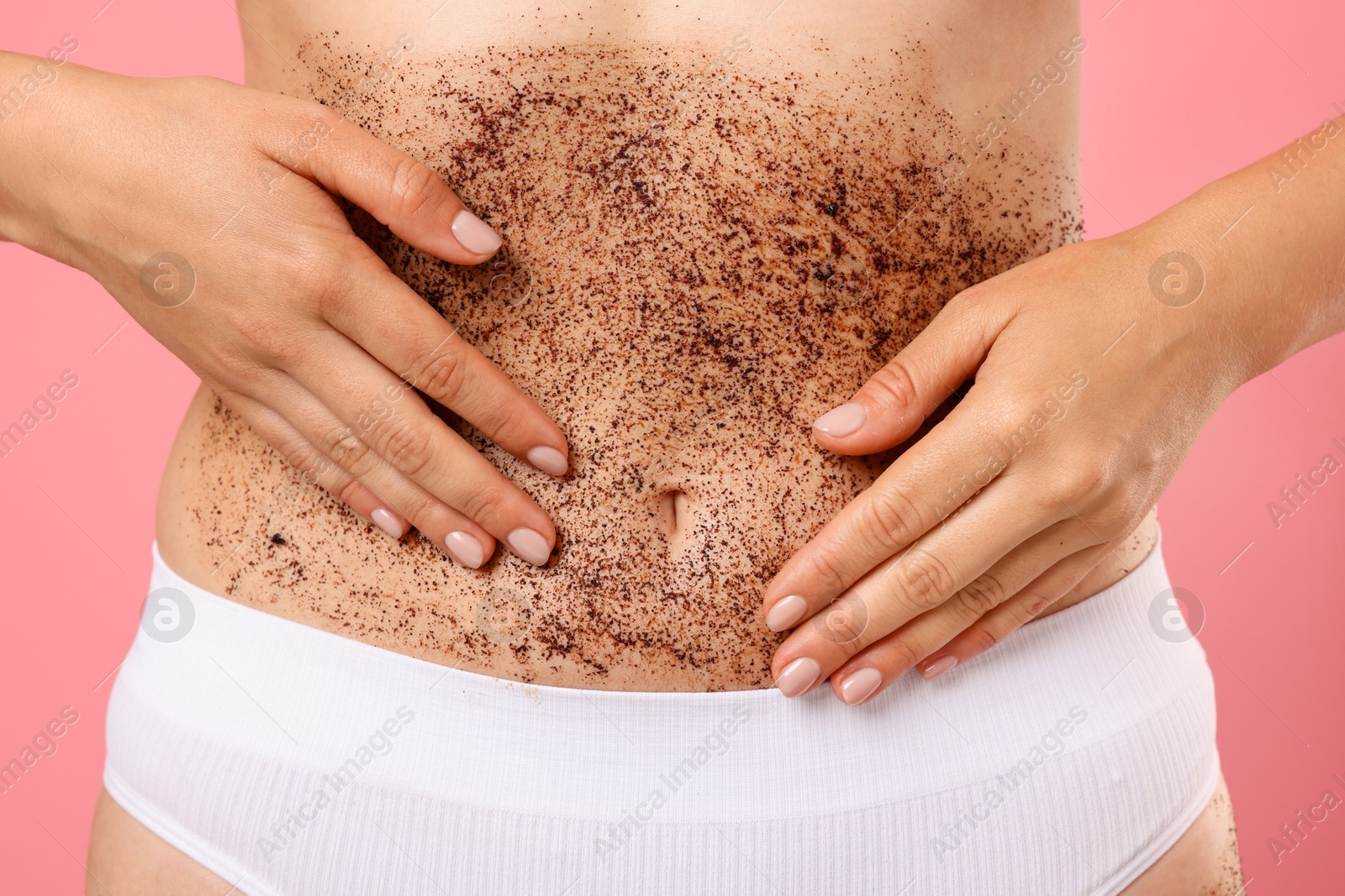 Woman applying body scrub onto her belly against pink background, closeup Photo of Woman applying body scrub onto her belly against pink background, closeup