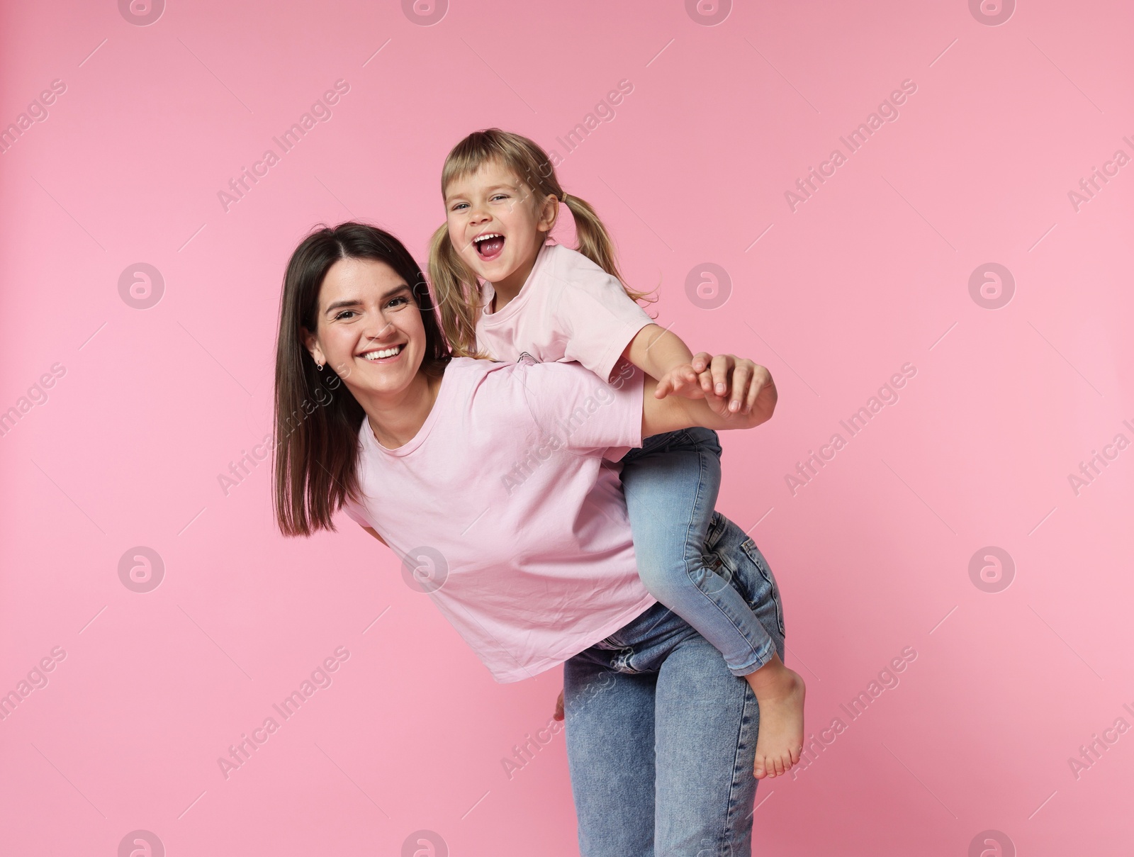 Happy mother and her cute daughter on pink background Photo of Happy mother and her cute daughter on pink background