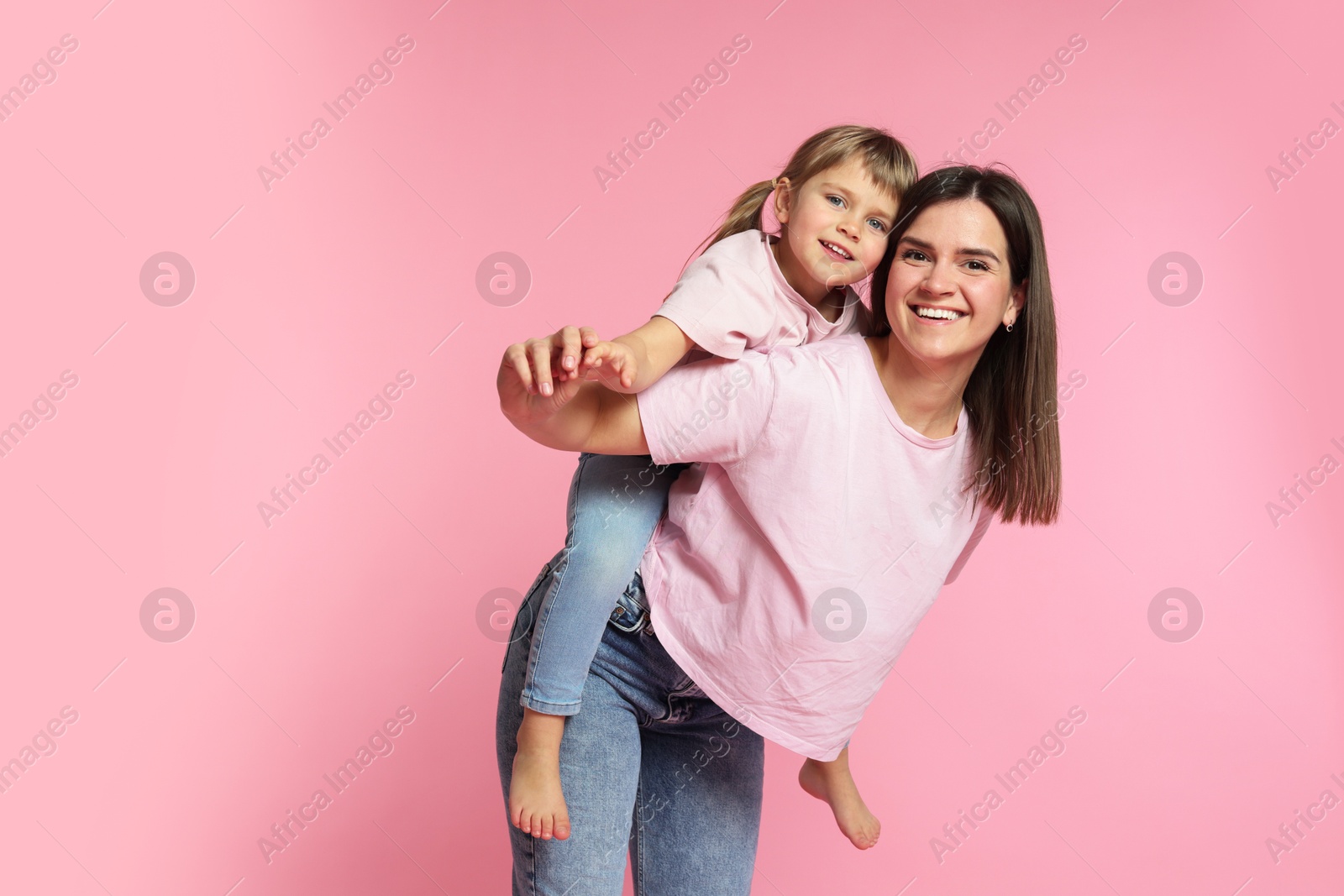Happy mother and her cute daughter on pink background Photo of Happy mother and her cute daughter on pink background