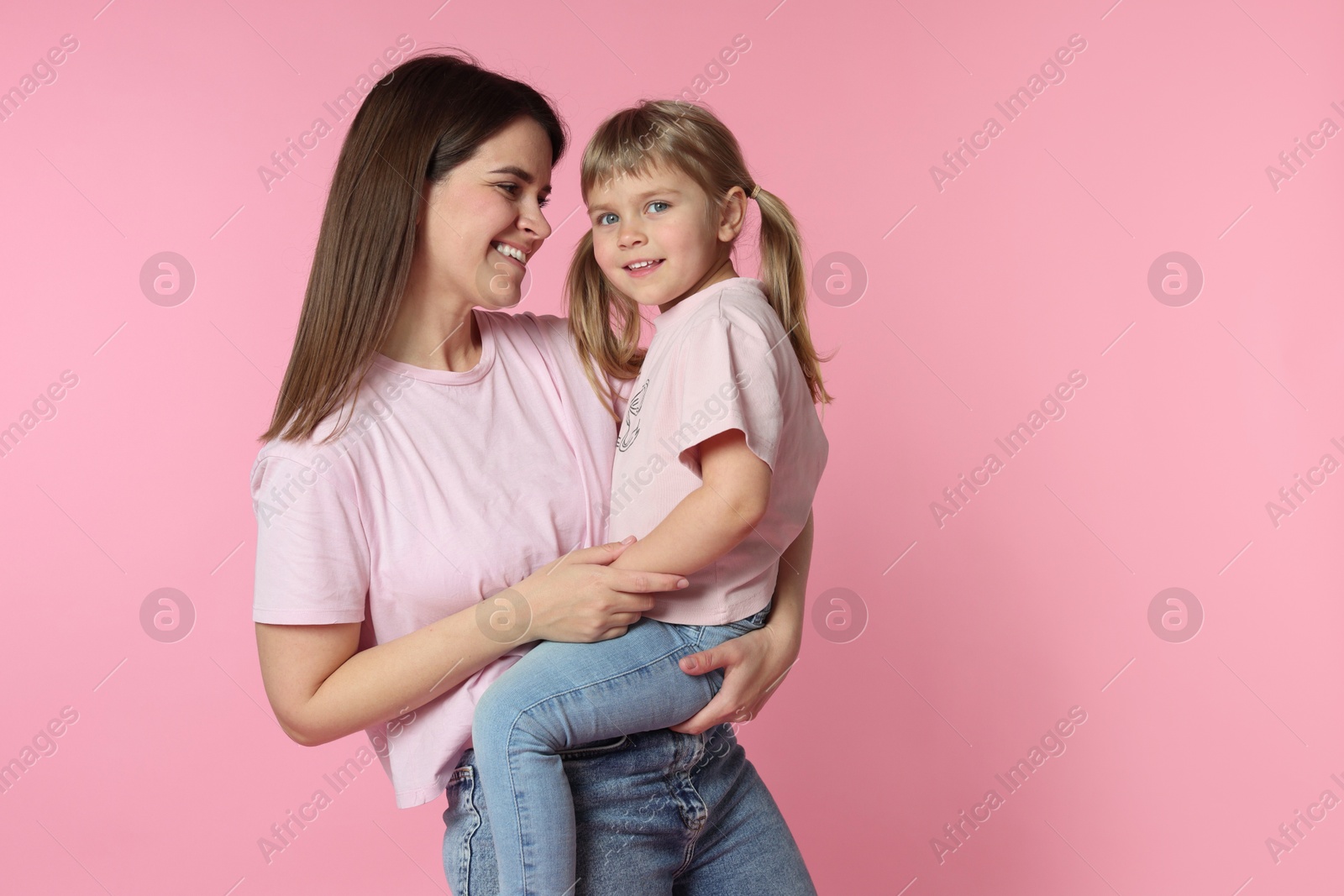Happy mother and her cute daughter on pink background Photo of Happy mother and her cute daughter on pink background