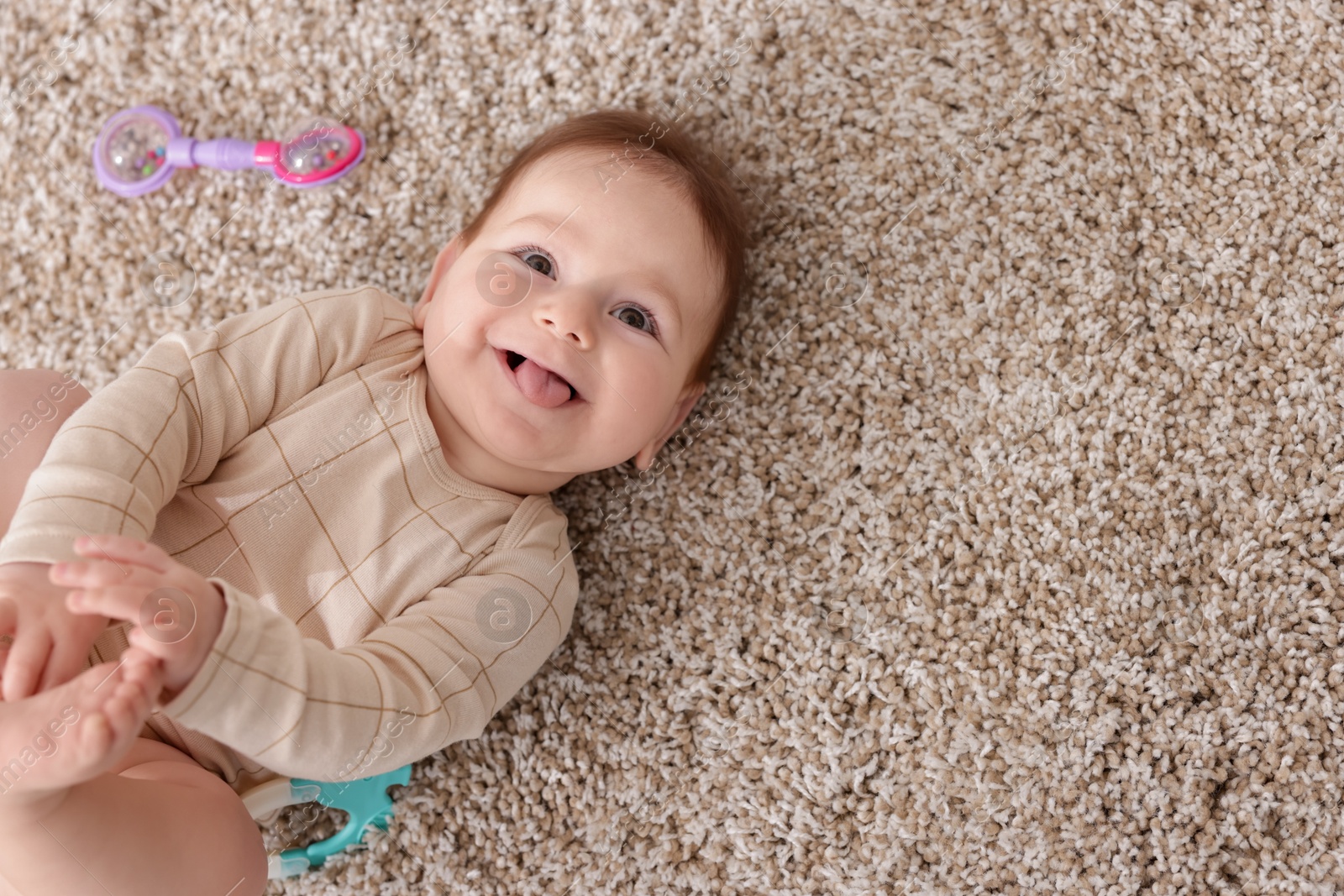 Cute little baby with rattle toy on floor at home, above view. Space for text Photo of Cute little baby with rattle toy on floor at home, above view. Space for text