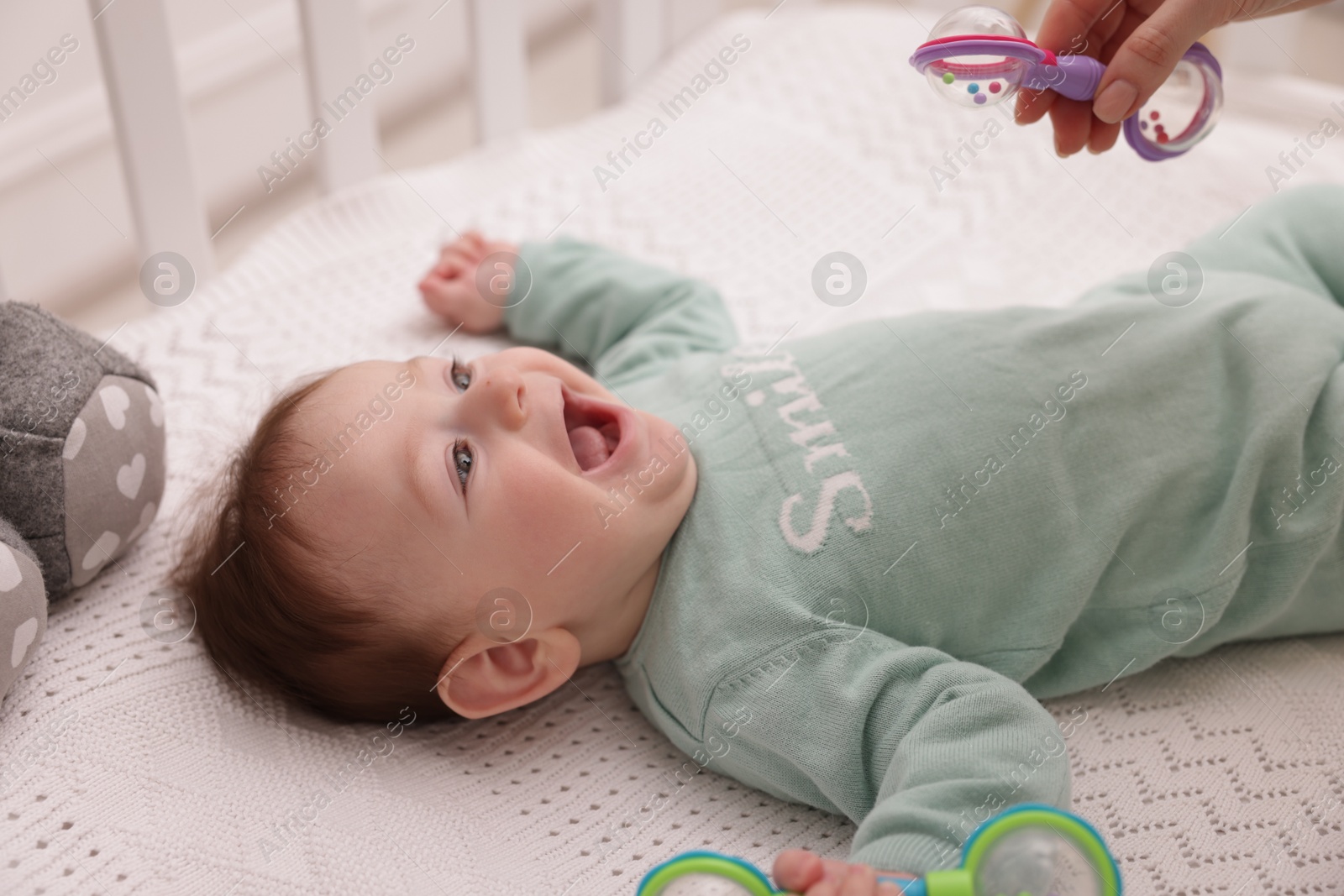 Cute little baby with rattle toy in crib at home Photo of Cute little baby with rattle toy in crib at home