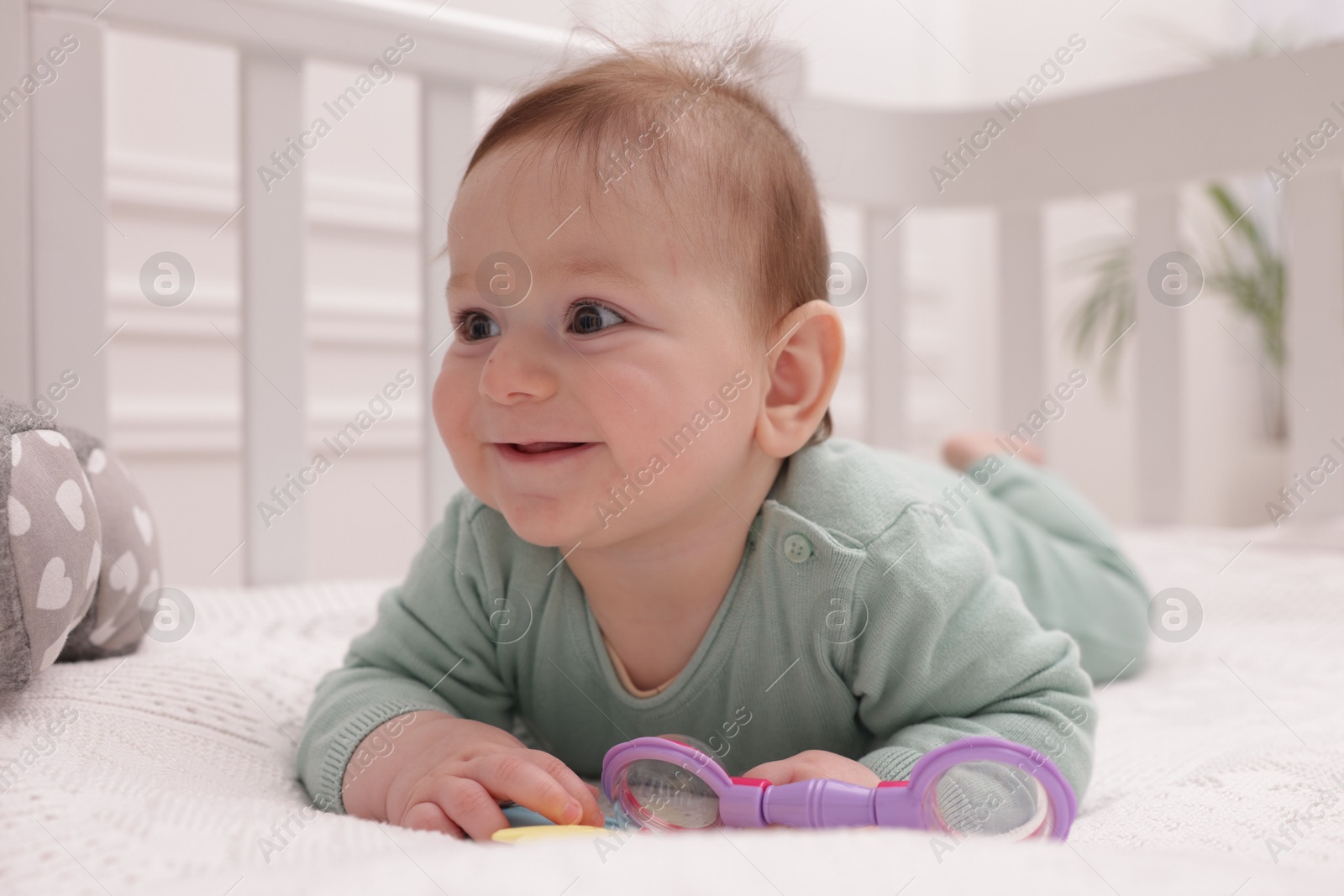 Cute little baby with rattle toy in crib at home Photo of Cute little baby with rattle toy in crib at home