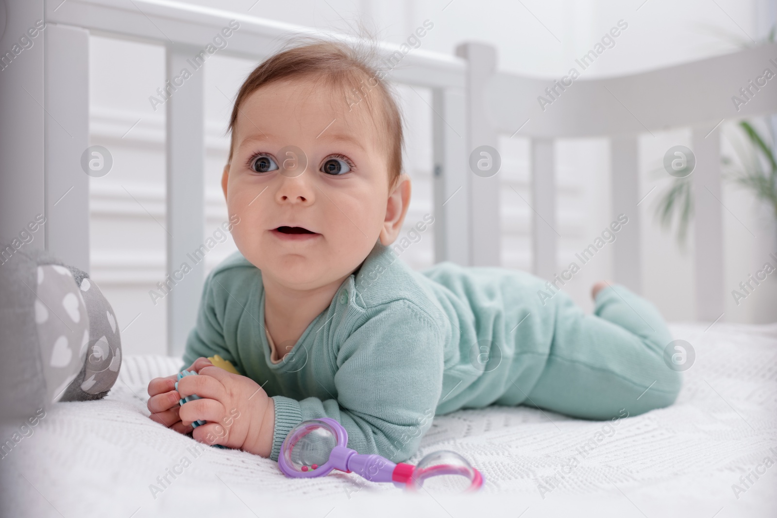 Cute little baby with rattle toy in crib at home Photo of Cute little baby with rattle toy in crib at home