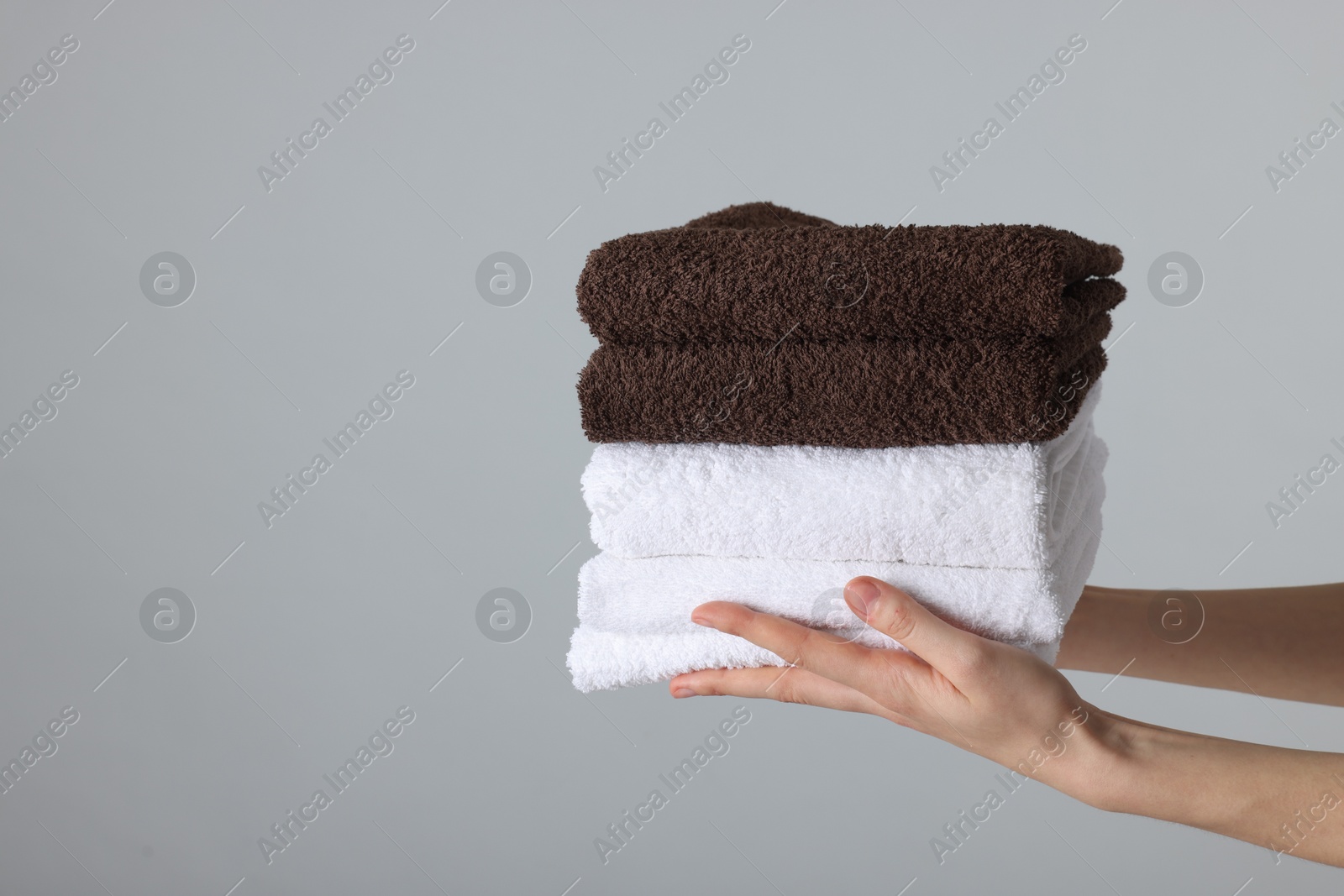 Woman holding stack of clean towels on light background, closeup. Space for text Photo of Woman holding stack of clean towels on light background, closeup. Space for text