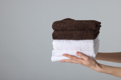 Photo of Woman holding stack of clean towels on light background, closeup. Space for text