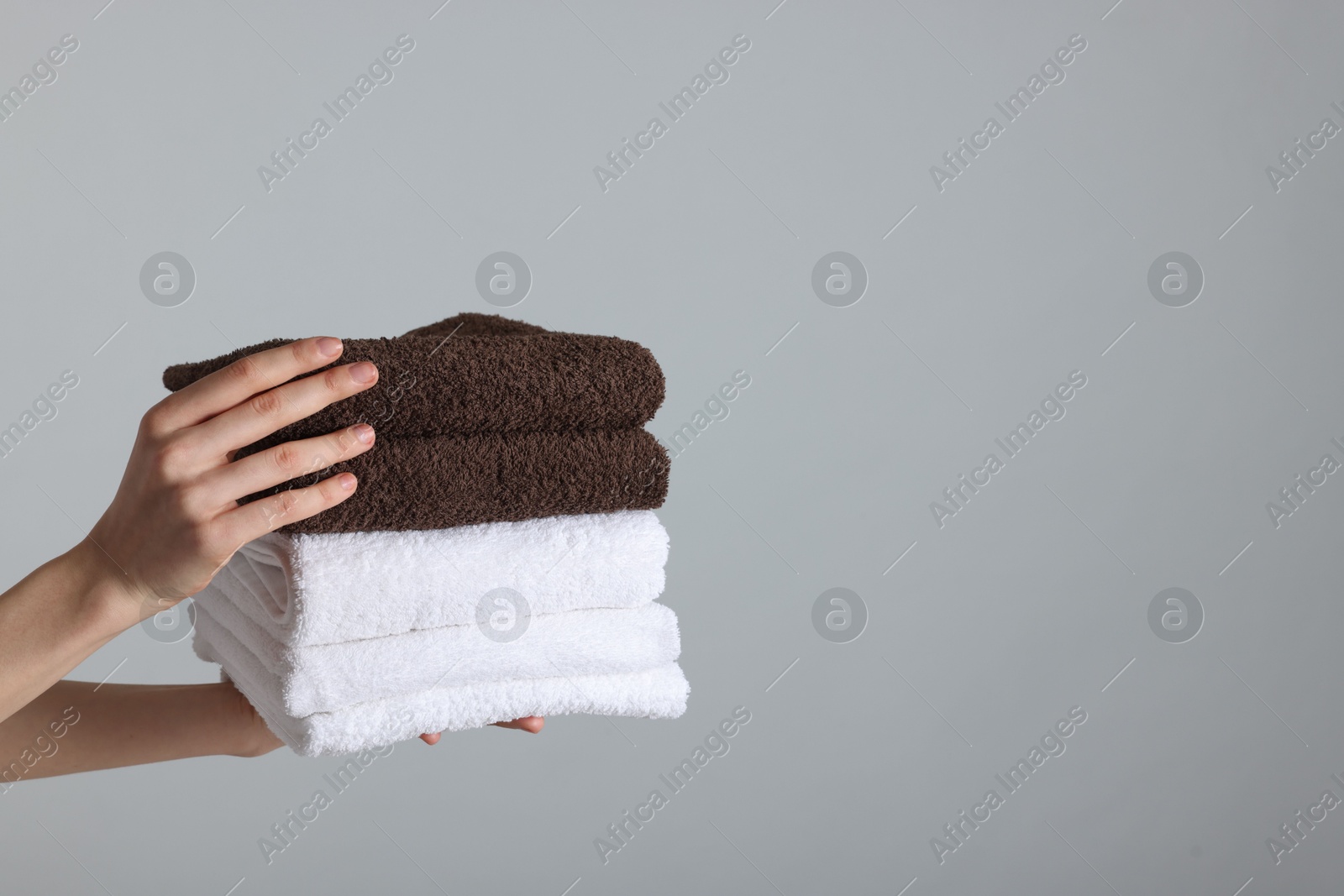 Woman holding stack of clean towels on light background, closeup. Space for text Photo of Woman holding stack of clean towels on light background, closeup. Space for text