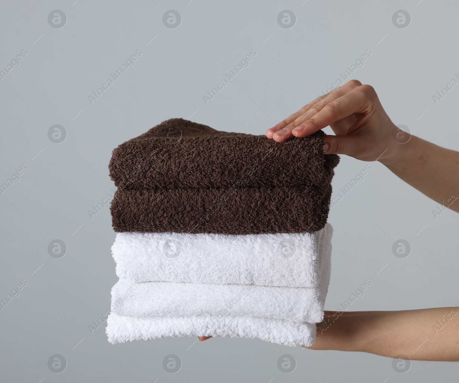 Woman holding stack of clean towels on light background, closeup Photo of Woman holding stack of clean towels on light background, closeup