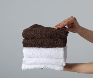 Photo of Woman holding stack of clean towels on light background, closeup