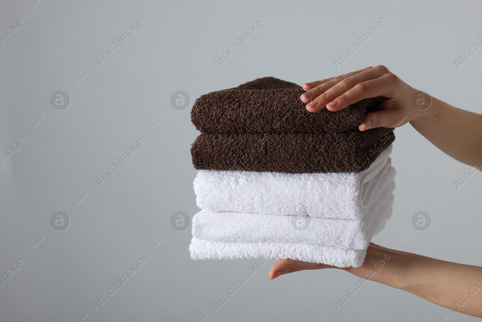 Woman holding stack of clean towels on light background, closeup. Space for text Photo of Woman holding stack of clean towels on light background, closeup. Space for text