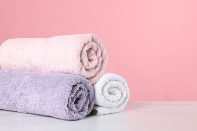 Photo of Clean towels on light marble table against pink background, closeup. Space for text
