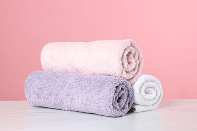 Photo of Clean towels on light marble table against pink background