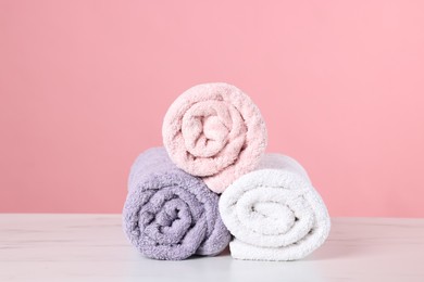 Photo of Clean towels on light marble table against pink background