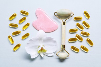 Photo of Collagen capsules, face roller, gua sha and flower on white background, flat lay