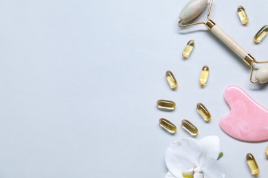 Photo of Collagen capsules, face roller, gua sha and flower on white background, flat lay. Space for text