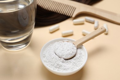 Photo of Collagen capsules, hair lock, powder, water and comb on beige background, closeup