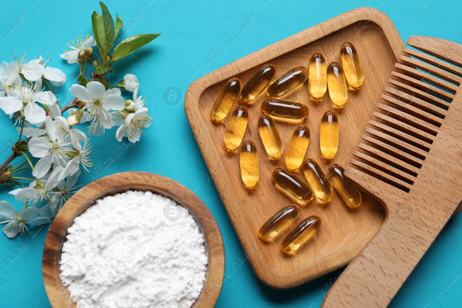 Collagen capsules, comb, powder and blossoms on light blue background, flat lay Photo of Collagen capsules, comb, powder and blossoms on light blue background, flat lay