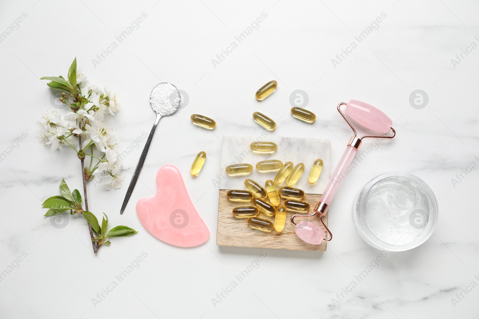 Flat lay composition with collagen capsules and blossoms on white marble table Photo of Flat lay composition with collagen capsules and blossoms on white marble table